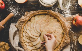 woman laying apple slices in pie crust to make an apple pie