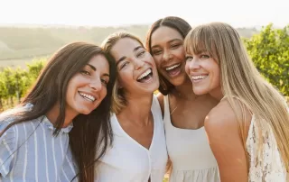 group of happy girl friends taking a group photo in a vineyard
