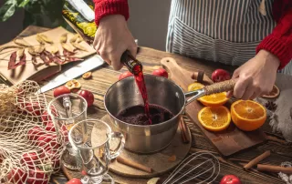 woman making mulled wine with spices and fruits in a pot